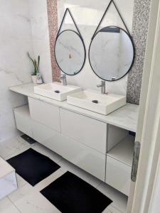 een witte badkamer met 2 wastafels en 2 spiegels bij La Villa Blanca Montpellier Piscine & proximité Mer in Saint-Jean-de-Védas