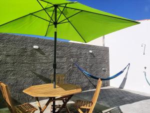 a table and two chairs with a green umbrella at Casa do Bairro in Horta