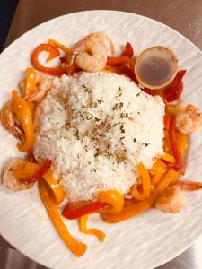 a white plate with rice and shrimp and vegetables at Knotty Pine Ocean Front Cabin - Adults Only in Ingonish Beach
