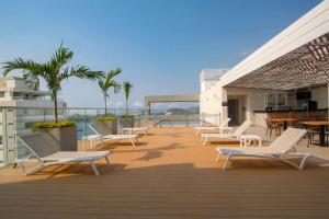 een terras met witte stoelen en tafels en palmbomen bij Hilton Garden Inn Santa Marta in Santa Marta