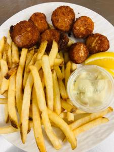 a plate of food with fries and meatballs and a lemon at Knotty Pine Ocean Front Cabin - Adults Only in Ingonish Beach