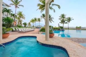 una piscina en un complejo con palmeras en Embassy Suites by Hilton Dorado del Mar Beach Resort, en Dorado