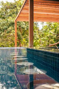 una piscina con tetto in legno e riflessi in acqua di Pousada e Restaurante Amazonia ad Alter do Chão