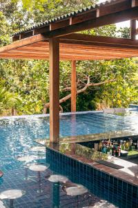 a swimming pool with stools under a wooden pergola at Pousada e Restaurante Amazonia in Alter do Chao