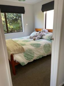 a teddy bear laying on a bed in a bedroom at Bach on Daisy in Tauranga