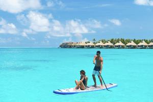 een man en een vrouw op een paddleboard in de oceaan bij Conrad Bora Bora Nui in Bora Bora
