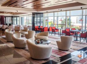 um restaurante com cadeiras, mesas e janelas em Hilton Garden Inn Montevideo em Montevidéu