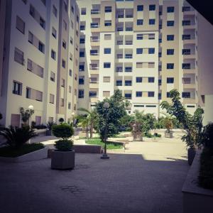 un grand bâtiment avec une cour plantée d'arbres et de buissons dans l'établissement Super Apartement Totalement neuf a Marjane, à Tanger
