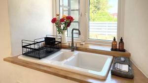 a kitchen sink with a vase of flowers and a window at Beautiful Rural Cottage by the Coast in East Portlemouth