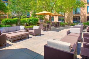 un patio con sillas, mesas y una sombrilla en Courtyard by Marriott Ann Arbor, en Ann Arbor