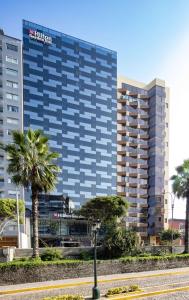 a tall building with palm trees in front of it at Hilton Garden Inn Lima Miraflores in Lima