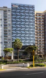 un edificio alto con palmeras frente a una calle en Hilton Garden Inn Lima Miraflores, en Lima