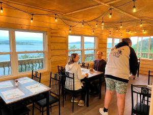 eine Gruppe von Menschen, die an einem Tisch in einem Restaurant sitzen in der Unterkunft Knotty Pine Cottages, Suites & Motel Rooms in Ingonish Beach