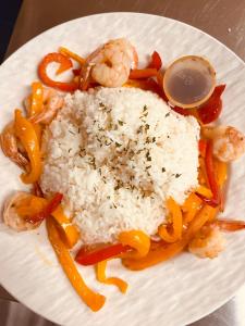 a white plate with rice and shrimp and vegetables at Knotty Pine Cottages, Suites & Motel Rooms in Ingonish Beach