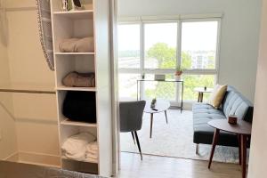 a room with a book shelf with a couch and a window at Modern Queen Bed & Twin Futon Studio with WiFi, Kitchen, Washer, and Dryer in Charlotte