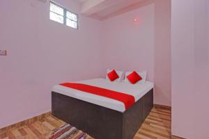 um quarto branco com uma cama com almofadas vermelhas em Flagship Red Rose Hotel & Banquet em Dhanbad