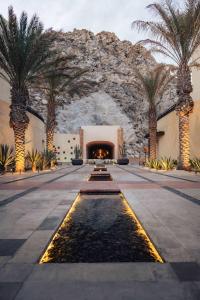 une cour avec des palmiers dans un bâtiment avec une fontaine dans l'établissement Waldorf Astoria Los Cabos Pedregal, à Cabo San Lucas