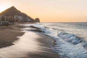 a beach at sunset with a mountain in the background at Waldorf Astoria Los Cabos Pedregal in Cabo San Lucas