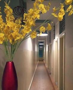 a red vase with yellow flowers in a hallway at Stylo Hotel in Juiz de Fora