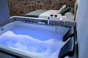 a blue tub with wine glasses and a bed at El Esquileo in Buitrago del Lozoya