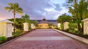 uma entrada que leva a uma casa com palmeiras em Hilton Hotel Tahiti em Papeete