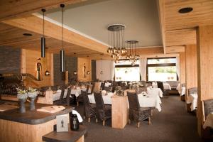 um restaurante com mesas e cadeiras brancas e um lustre em Hotel Die Montafonerin em Vandans