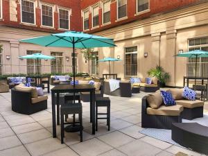 un patio con sofás, mesas y sombrillas azules en DoubleTree by Hilton Hotel Boston - Downtown en Boston