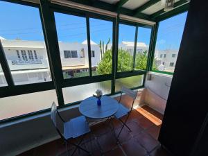 einen Tisch und Stühle in einem Zimmer mit Fenstern in der Unterkunft Apartamento ANTOSOL in Playa Honda