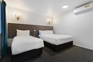 2 łóżka w pokoju hotelowym z białą pościelą w obiekcie Lakeview Colonial Motel w mieście Queenstown