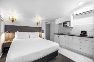 a white bedroom with a large bed and a kitchen at Lakeview Colonial Motel in Queenstown