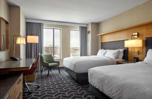 德梅因Hilton Des Moines Downtown的有两张床和一张书桌的酒店房间