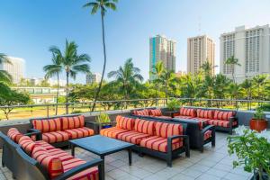 a row of chairs and tables on a balcony with a city at DoubleTree by Hilton Alana - Waikiki Beach in Honolulu