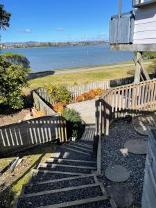 a set of stairs leading to a house with a view of the water at Bach on Daisy in Tauranga