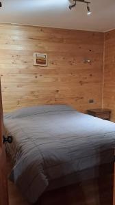 een slaapkamer met een bed met een houten muur bij GLAMPING CABAÑA HOLMBERG in Coihaique