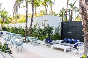 a patio with tables and chairs and palm trees at The Beverly Hilton in Los Angeles
