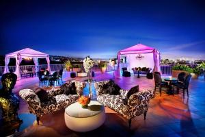 een patio met banken en tafels en roze tuinhuisjes bij The Beverly Hilton in Los Angeles