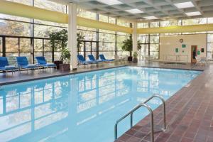 a large swimming pool with blue chairs and windows at DoubleTree by Hilton Kansas City - Overland Park in Overland Park