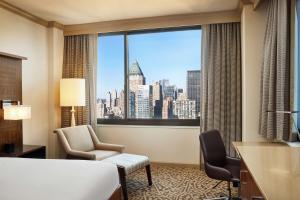 een hotelkamer met uitzicht op de stad vanuit een raam bij Hilton New York Times Square in New York