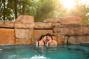 a man and a woman sitting in a swimming pool at Hilton Orlando Lake Buena Vista - Disney Springs™ Area in Orlando
