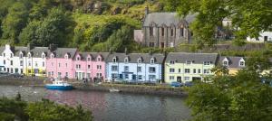 a row of houses next to a river with a boat at Quayside Apartment in Portree