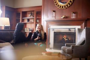 dos mujeres sentadas en el suelo frente a una chimenea en The Inn at Penn, A Hilton Hotel, en Filadelfia