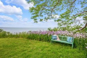 a woman sitting on a bench next to a field of flowers at Beautiful Lakeside Haven in Port Hope