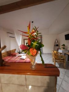 eine Vase mit Blumen auf einem Tisch in einem Schlafzimmer in der Unterkunft Appartement à la campagne avec spa 3 nuits minimum in Le Lamentin
