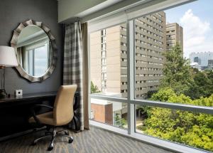 una oficina con escritorio, espejo y ventana en The Inn at Penn, A Hilton Hotel, en Filadelfia