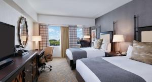 um quarto de hotel com duas camas e uma televisão em The Inn at Penn, A Hilton Hotel em Filadélfia
