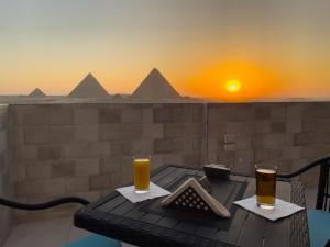 deux verres de bière sur une table avec vue sur les pyramides dans l'établissement Jumeirah pyramids view inn, au Caire