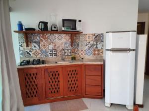 uma cozinha com um frigorífico branco e armários de madeira em kosomao 2 em Morro de São Paulo
