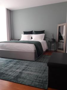 a bedroom with a large bed and a rug at Maia Centro in Maia