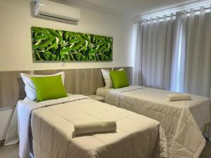 two beds with green pillows in a room at Casa no Alto da Pitinga-Arraial D'ajuda in Arraial d'Ajuda