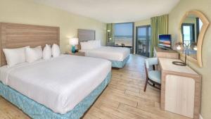 デイトナビーチにあるEl Caribe Resort and Conference Centerのベッド2台とテレビが備わるホテルルームです。